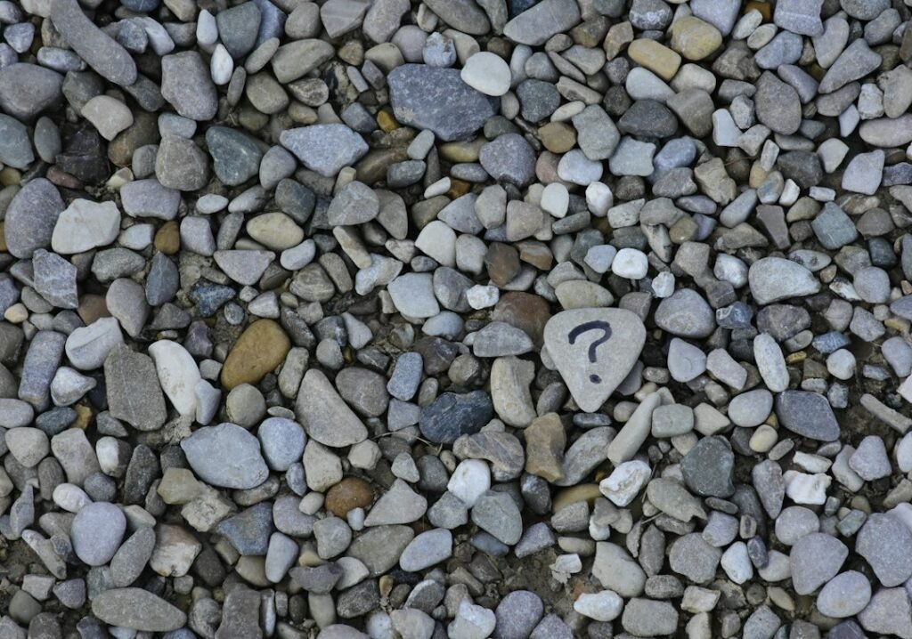 A question mark drawn on a pebble among grey stones